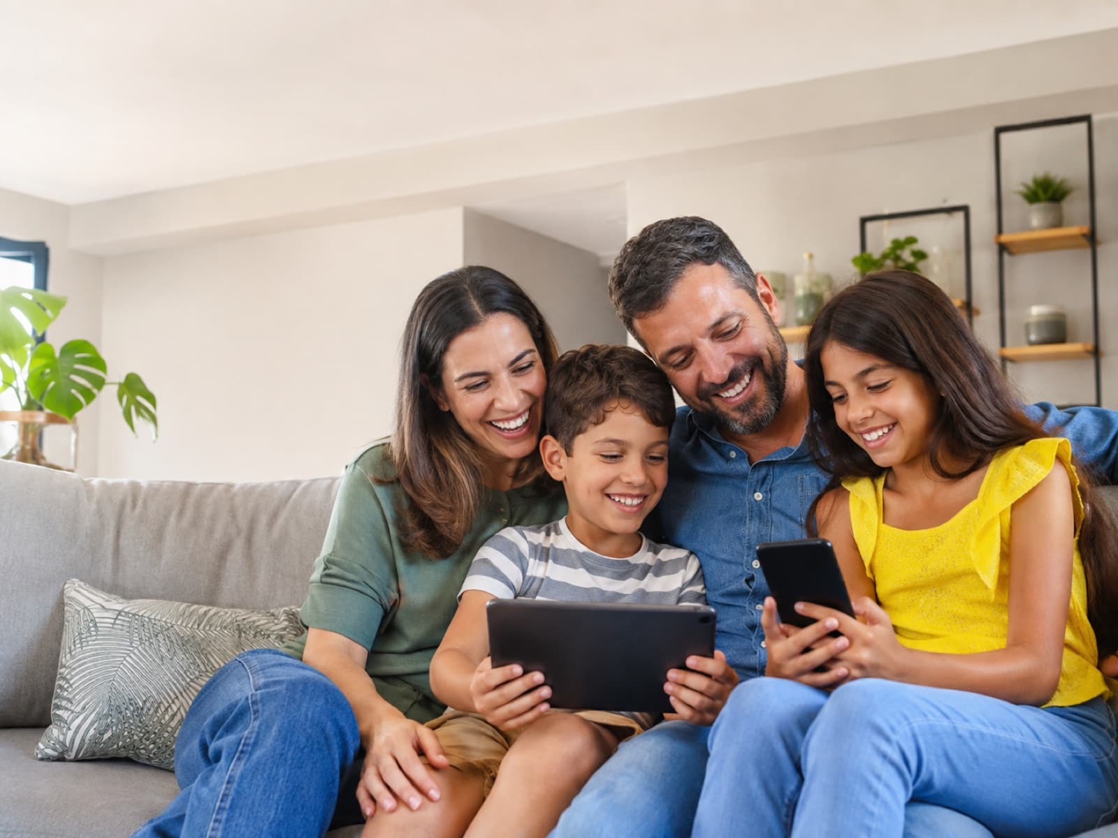Família reunida no sofá usando tablet e celular